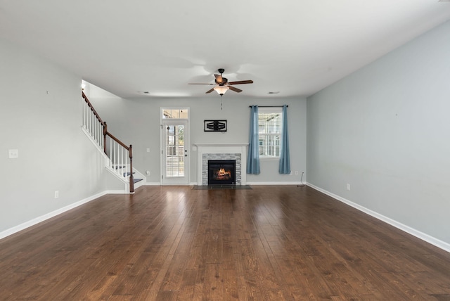 unfurnished living room featuring ceiling fan, a fireplace, and dark hardwood / wood-style floors