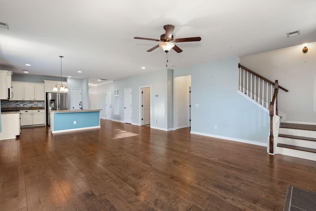 unfurnished living room featuring ceiling fan with notable chandelier, dark hardwood / wood-style floors, and sink