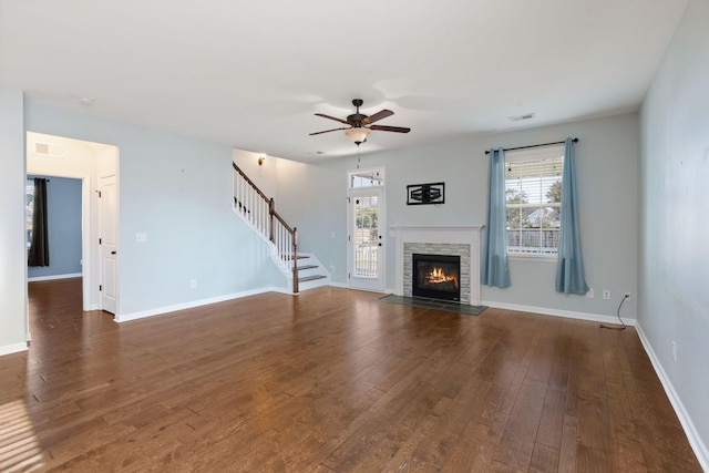 unfurnished living room with ceiling fan, dark hardwood / wood-style floors, and a stone fireplace