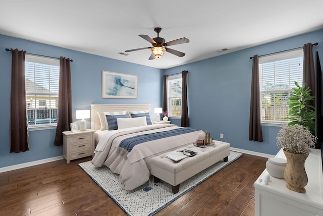 bedroom featuring ceiling fan, dark wood-type flooring, and multiple windows