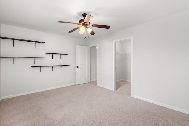 unfurnished bedroom featuring light carpet, ceiling fan, a walk in closet, and a closet