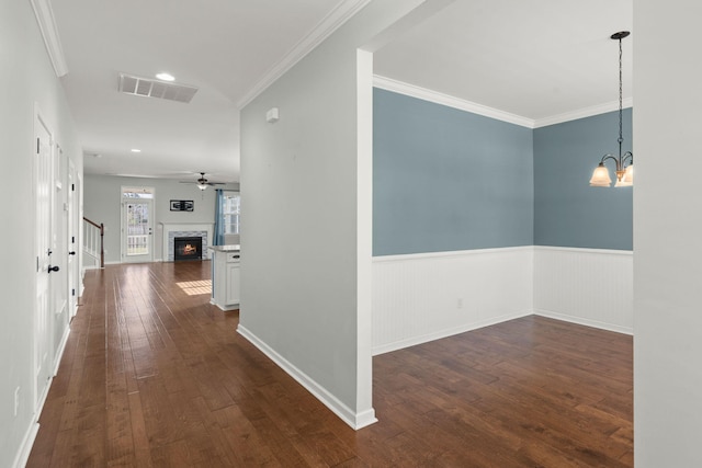 corridor with dark hardwood / wood-style floors, crown molding, and a notable chandelier