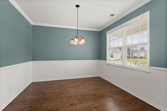 empty room featuring ornamental molding, a healthy amount of sunlight, dark hardwood / wood-style floors, and a notable chandelier