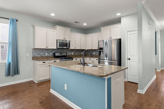 kitchen with stainless steel appliances, a kitchen island with sink, white cabinets, and sink