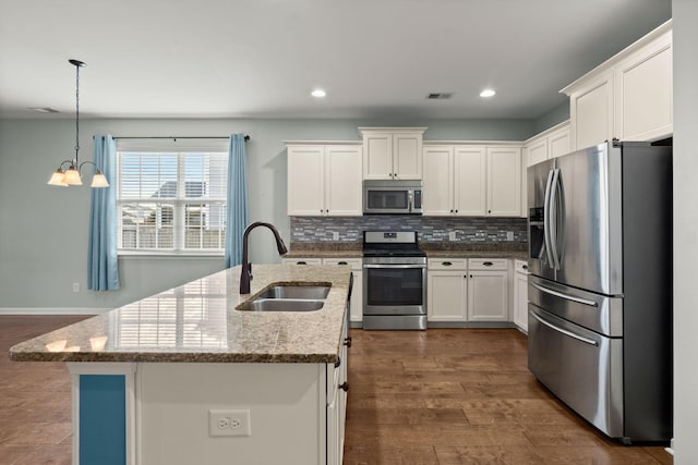 kitchen featuring stainless steel appliances, a chandelier, white cabinets, light stone counters, and sink