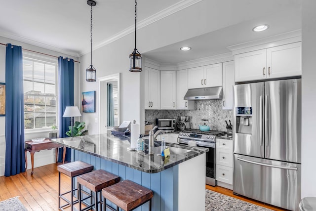 kitchen with dark stone counters, a kitchen breakfast bar, sink, white cabinetry, and stainless steel appliances