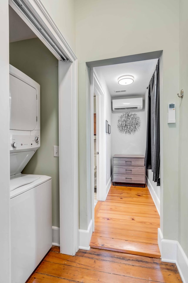 laundry room with a wall mounted air conditioner, hardwood / wood-style flooring, and stacked washer / dryer