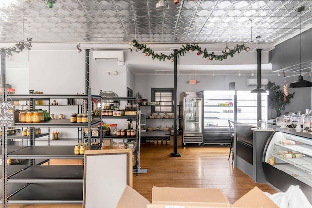 kitchen featuring wood-type flooring, track lighting, and a wall mounted AC