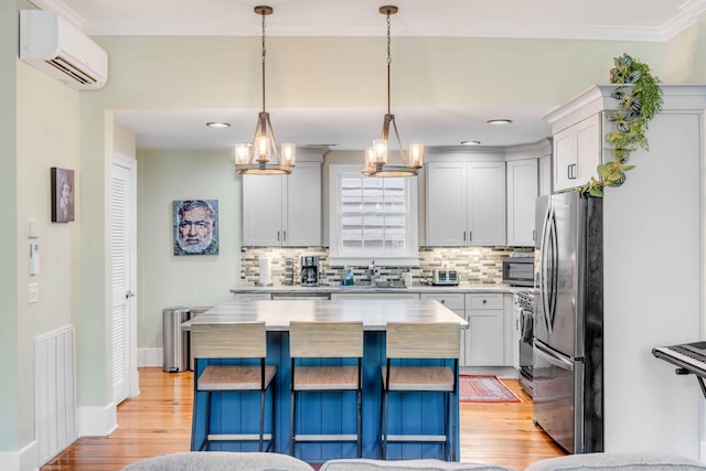 kitchen featuring decorative light fixtures, a center island, stainless steel appliances, and a wall unit AC