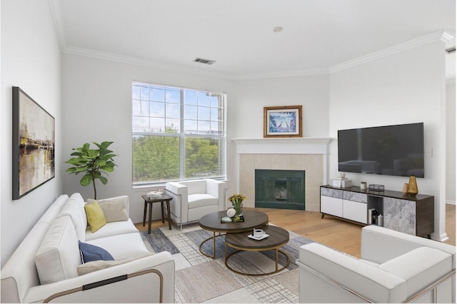 living area featuring visible vents, a fireplace, light wood-style flooring, and crown molding