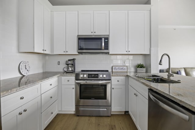 kitchen with appliances with stainless steel finishes, dark wood finished floors, white cabinets, and a sink