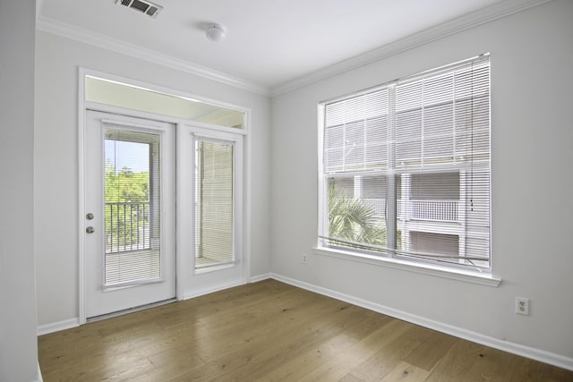 spare room featuring light wood-style flooring, visible vents, baseboards, and ornamental molding