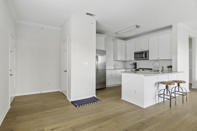 kitchen with stainless steel appliances, light countertops, white cabinets, and visible vents