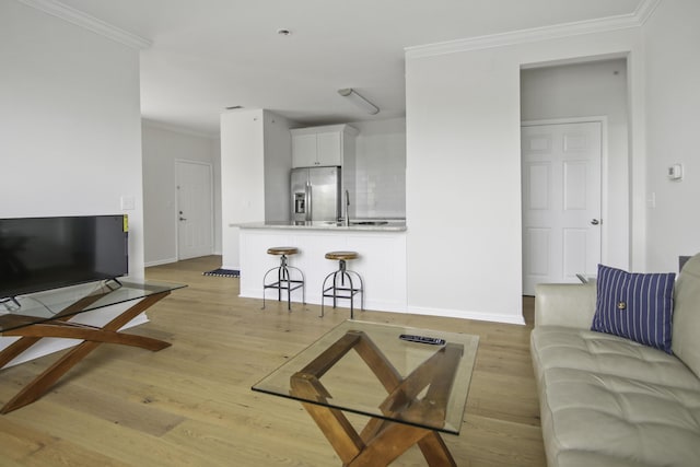 living room with light wood-style floors, ornamental molding, and baseboards