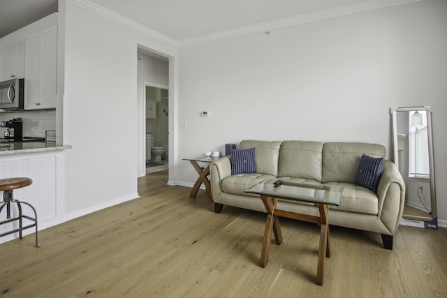 living area featuring crown molding, baseboards, and light wood-style floors