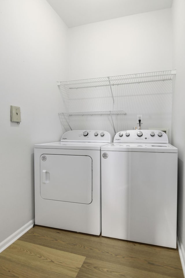 laundry room with washer and dryer, laundry area, baseboards, and wood finished floors