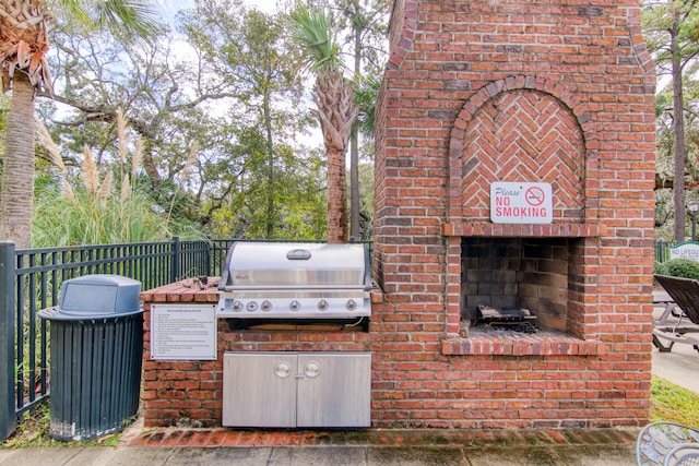 view of patio / terrace featuring an outdoor brick fireplace, a grill, and fence