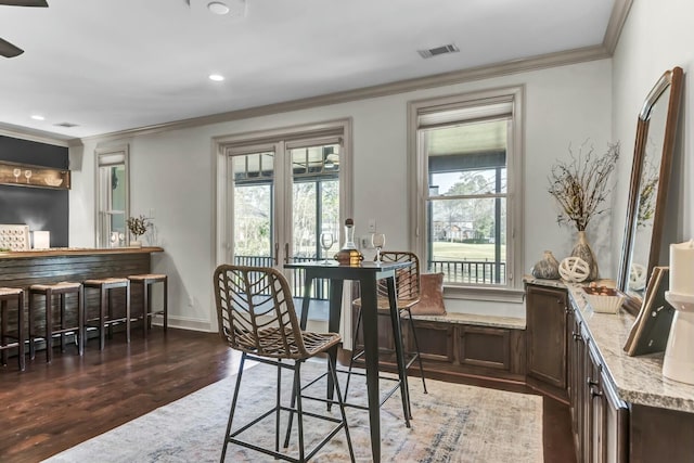 dining area with a wealth of natural light, wood finished floors, baseboards, and ornamental molding