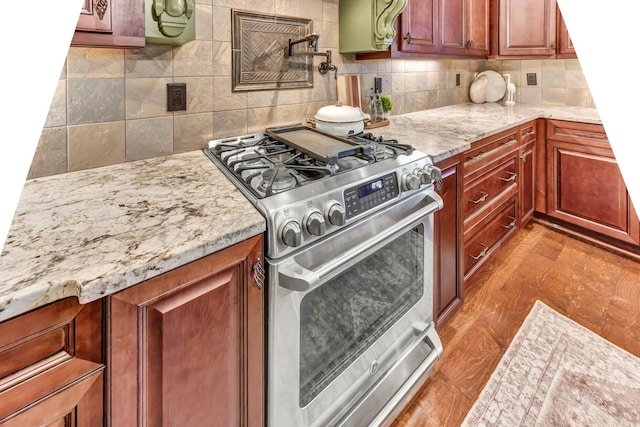 kitchen with light stone counters, gas range, and backsplash