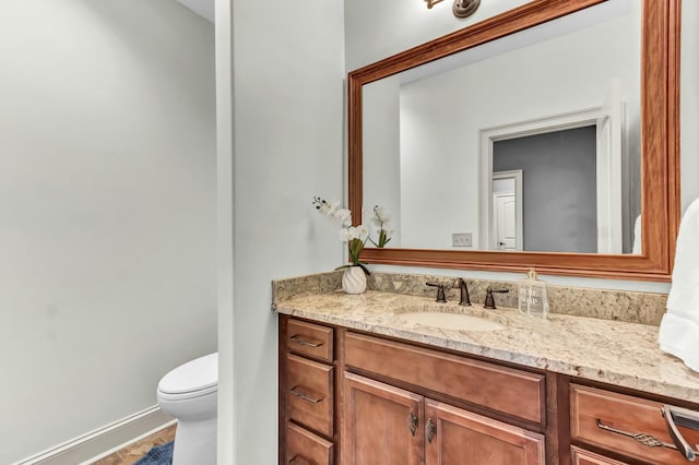 bathroom featuring vanity, toilet, and baseboards