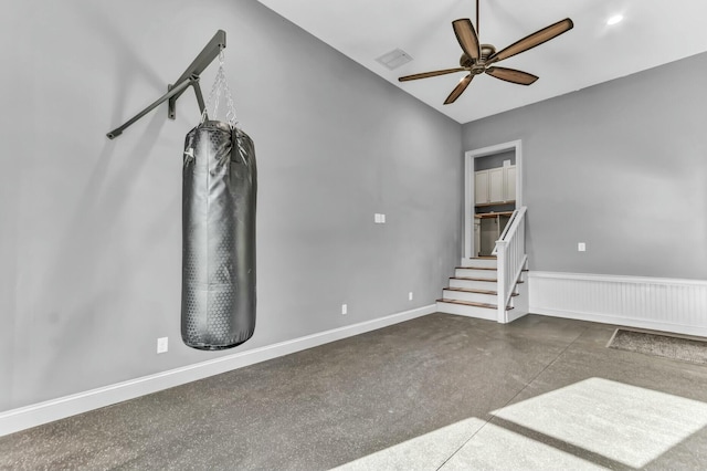 unfurnished living room featuring visible vents, baseboards, a wainscoted wall, and a ceiling fan