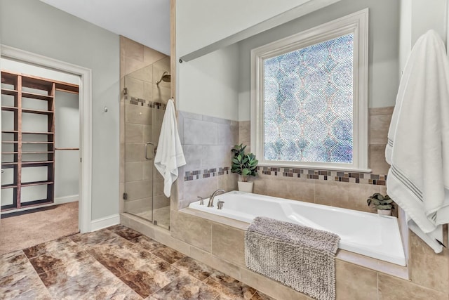 bathroom featuring a bath, a shower stall, and baseboards