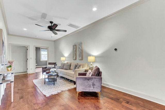 living room featuring wood finished floors, visible vents, baseboards, ceiling fan, and crown molding