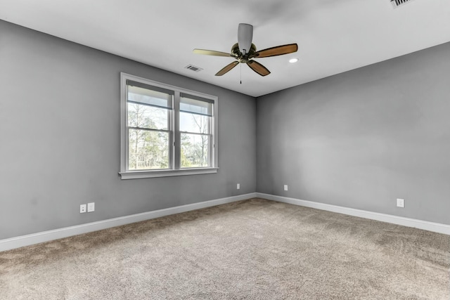 carpeted empty room with baseboards, visible vents, and ceiling fan