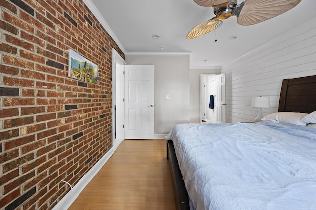 bedroom featuring ceiling fan, light wood-type flooring, crown molding, and brick wall