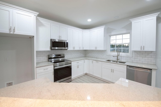 kitchen featuring decorative backsplash, white cabinets, light hardwood / wood-style flooring, sink, and stainless steel appliances