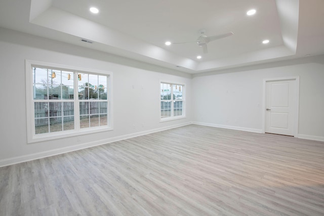 unfurnished room with ceiling fan, light wood-type flooring, and a raised ceiling