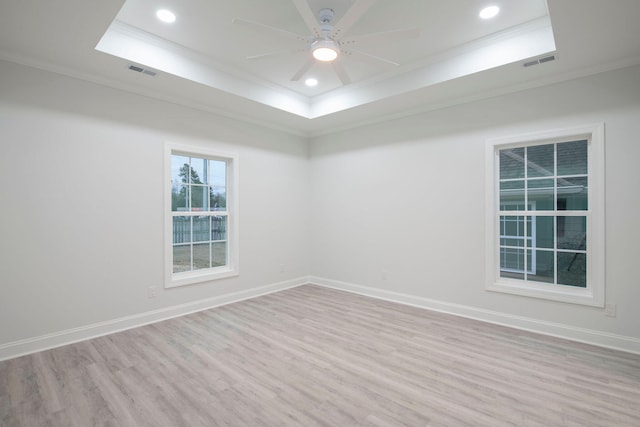 spare room featuring crown molding, light hardwood / wood-style flooring, ceiling fan, and a raised ceiling