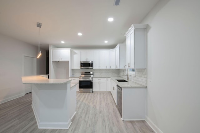 kitchen with sink, light wood-type flooring, hanging light fixtures, white cabinetry, and stainless steel appliances