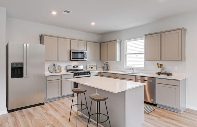 kitchen featuring gray cabinets, appliances with stainless steel finishes, light wood-type flooring, and a center island