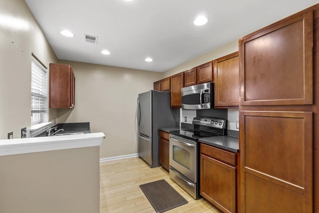 kitchen with appliances with stainless steel finishes and light hardwood / wood-style floors