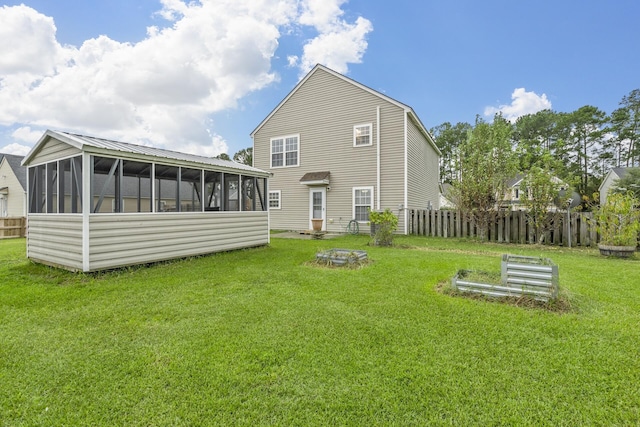 rear view of property featuring a sunroom and a lawn