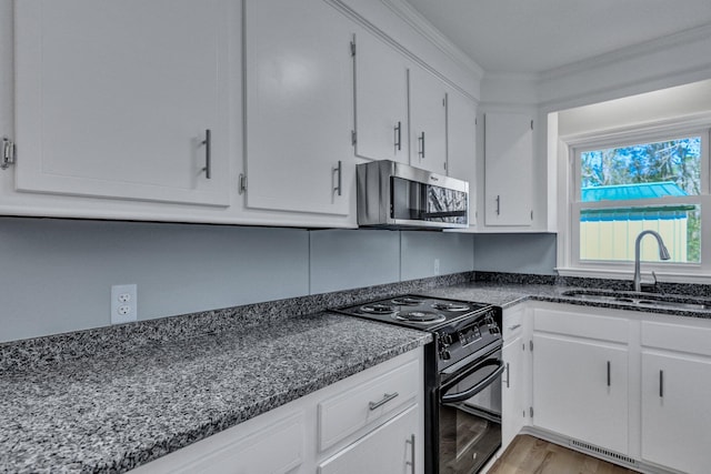 kitchen with electric range, visible vents, stainless steel microwave, white cabinetry, and a sink