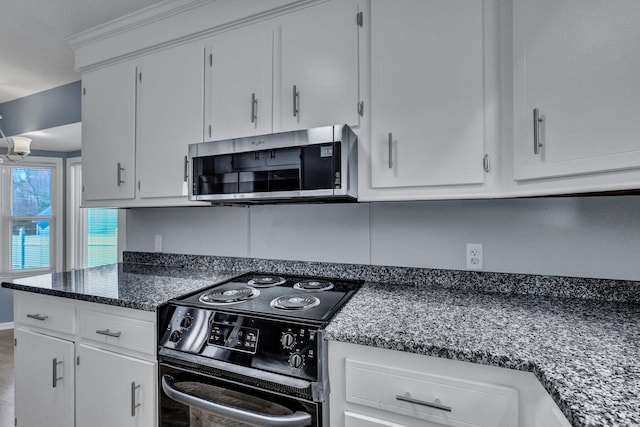 kitchen with dark stone counters, stainless steel microwave, electric range, and white cabinetry