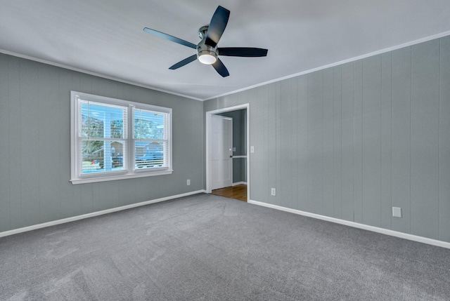 unfurnished bedroom featuring crown molding, dark carpet, baseboards, and a ceiling fan