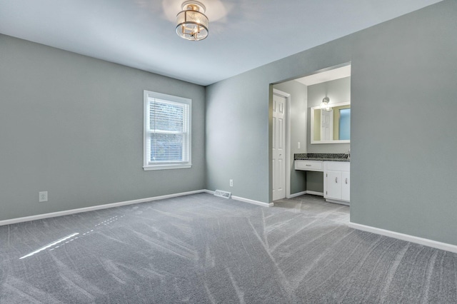 unfurnished bedroom with visible vents, light carpet, connected bathroom, a chandelier, and baseboards