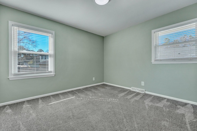 carpeted spare room with plenty of natural light, visible vents, and baseboards