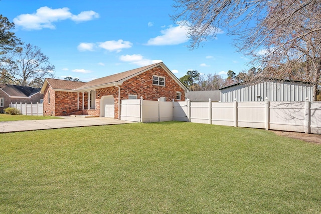 view of yard with driveway, fence private yard, and a garage