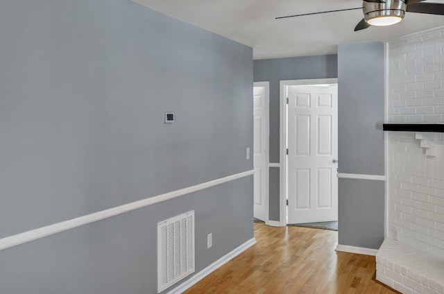 hallway with visible vents, light wood-style flooring, and baseboards