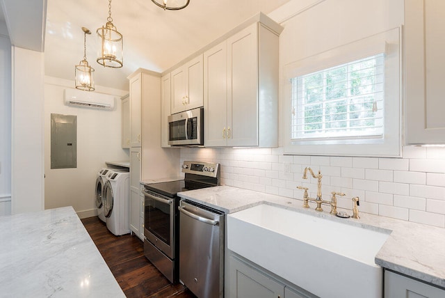 kitchen with a wall mounted AC, decorative light fixtures, appliances with stainless steel finishes, dark hardwood / wood-style floors, and washing machine and dryer