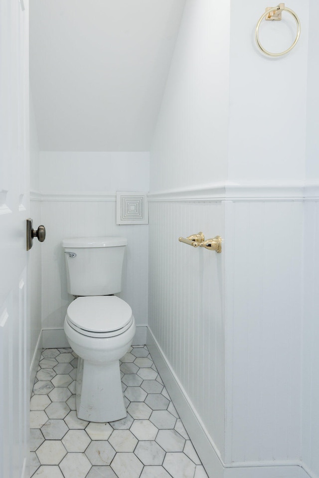 bathroom with lofted ceiling, toilet, and tile patterned floors