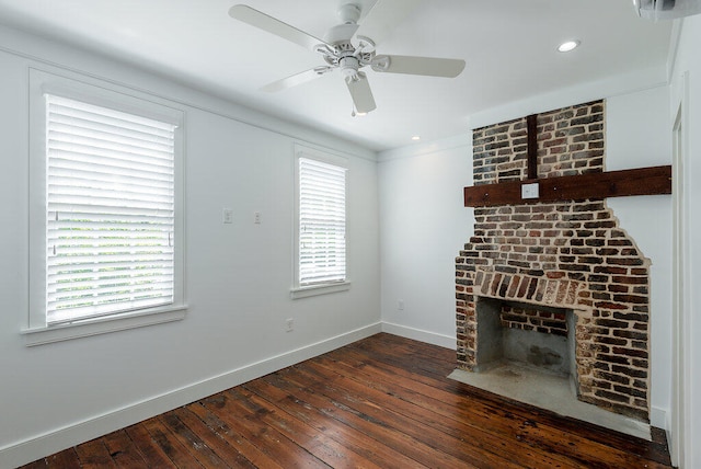 unfurnished living room with a brick fireplace, a wealth of natural light, ceiling fan, and dark hardwood / wood-style floors