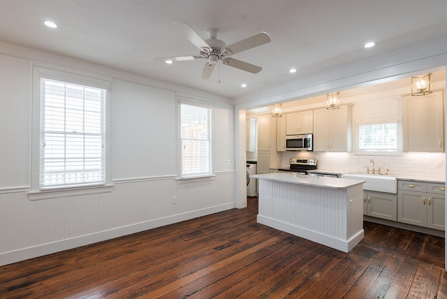 kitchen with sink, a center island, stainless steel appliances, washer / dryer, and dark hardwood / wood-style flooring