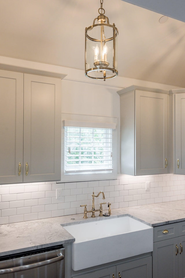 kitchen with pendant lighting, sink, gray cabinetry, stainless steel dishwasher, and decorative backsplash