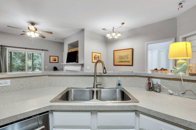 kitchen with stainless steel dishwasher, ceiling fan with notable chandelier, white cabinets, and sink