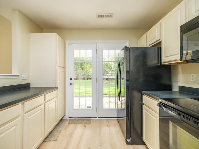 kitchen featuring light wood-style floors, dark countertops, and black appliances